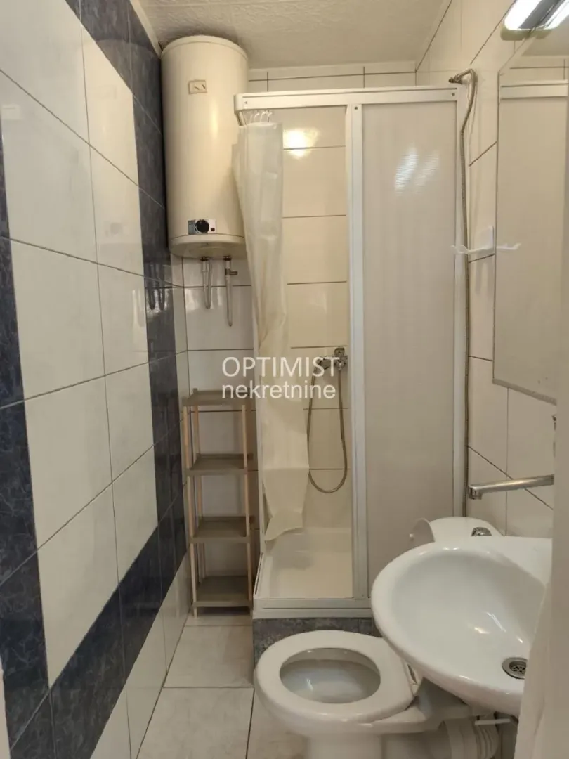 Smaller bathroom with a shower cabin, washbasin, and water heater.