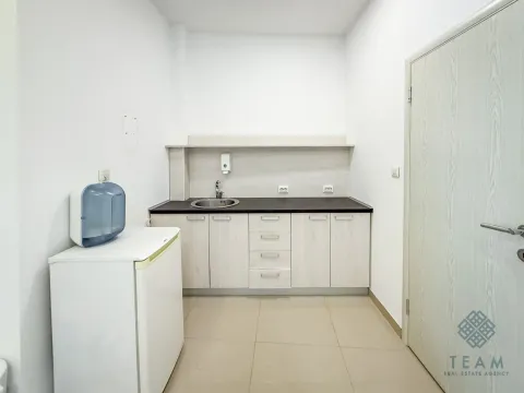 Small kitchenette with white units, a sink, and a small refrigerator. - image 14