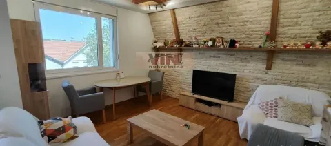 Dnevna soba sa garniturom, TV-om, trpezarijskim stolom i kosim plafonom sa drvenim gredama. - image 19