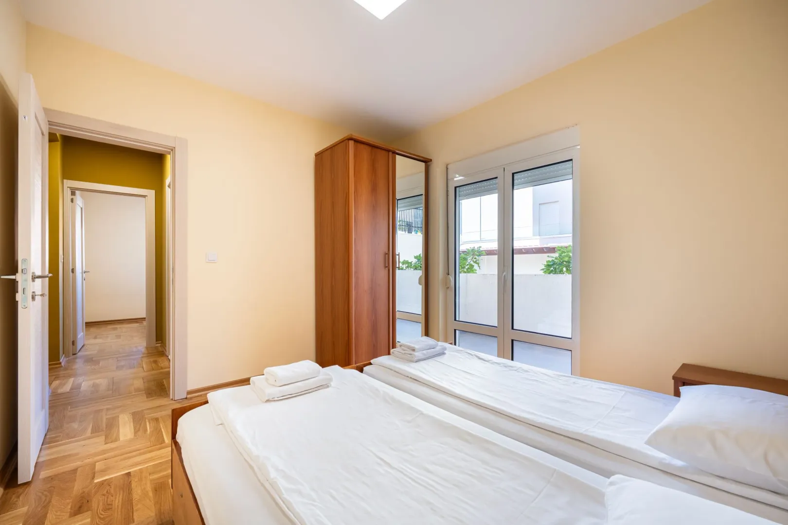 Furnished bedroom with two single beds and terrace access.