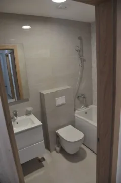 Modern bathroom with a bathtub, toilet, and sink vanity. - image 6