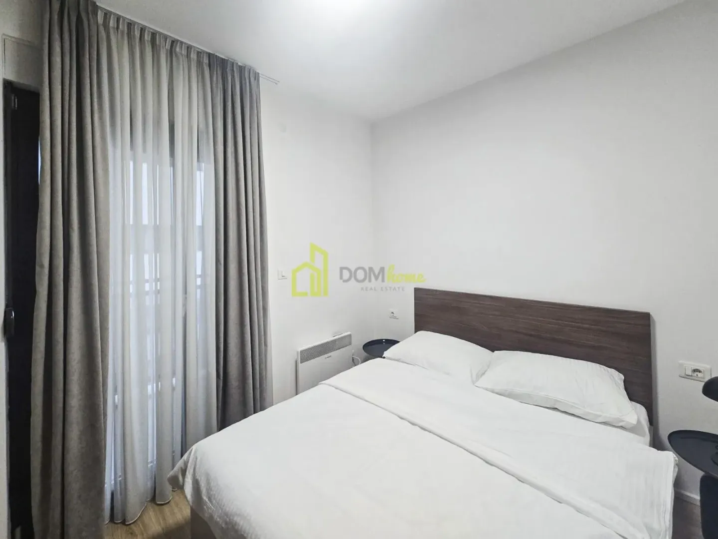 Bedroom with a double bed and a window with curtains.