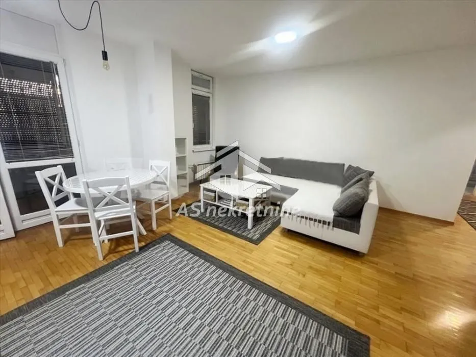 Living room with a sofa set, dining table and hardwood flooring.