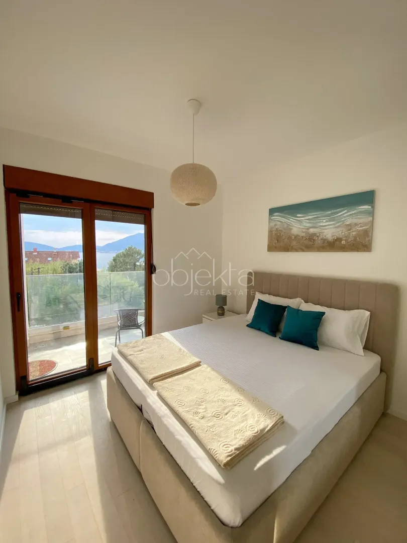 Furnished bedroom with a double bed and access to a terrace with a sea view.