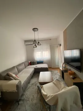 Dnevna soba sa ugaonom garniturom, stočićem i televizorom na zidu. - image 2
