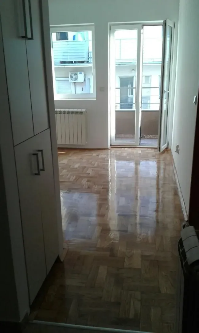 Prazna soba sa parketom i izlazom na terasu.