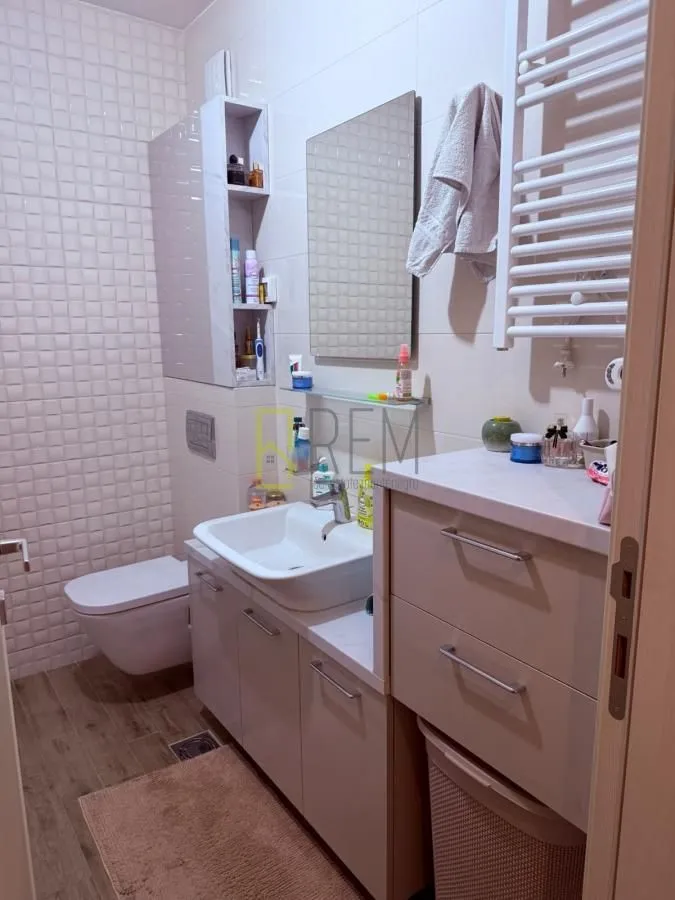 Modernly equipped bathroom with a sink, toilet, and storage units.