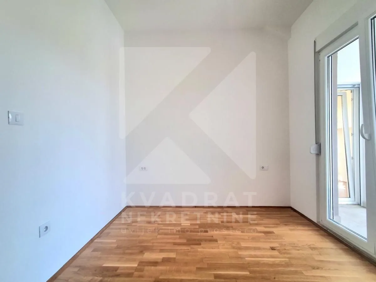 Empty room with parquet flooring and balcony doors.