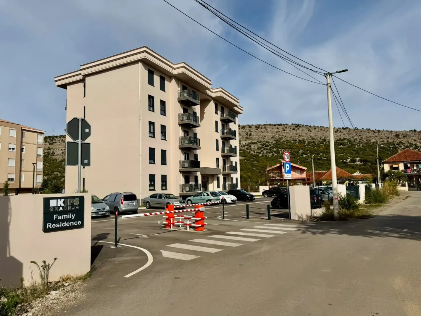 Eksterijer stambene zgrade sa parkingom i rampom.