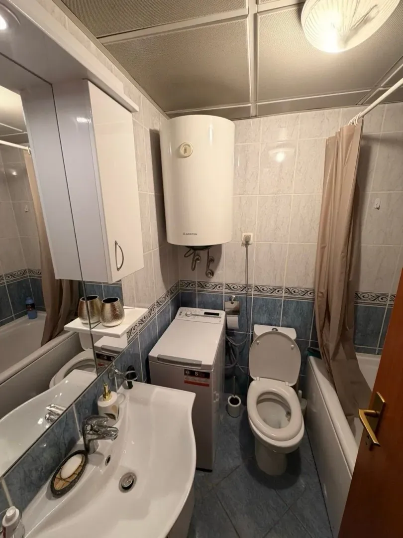 Small bathroom with a sink, toilet, bathtub, and washing machine.