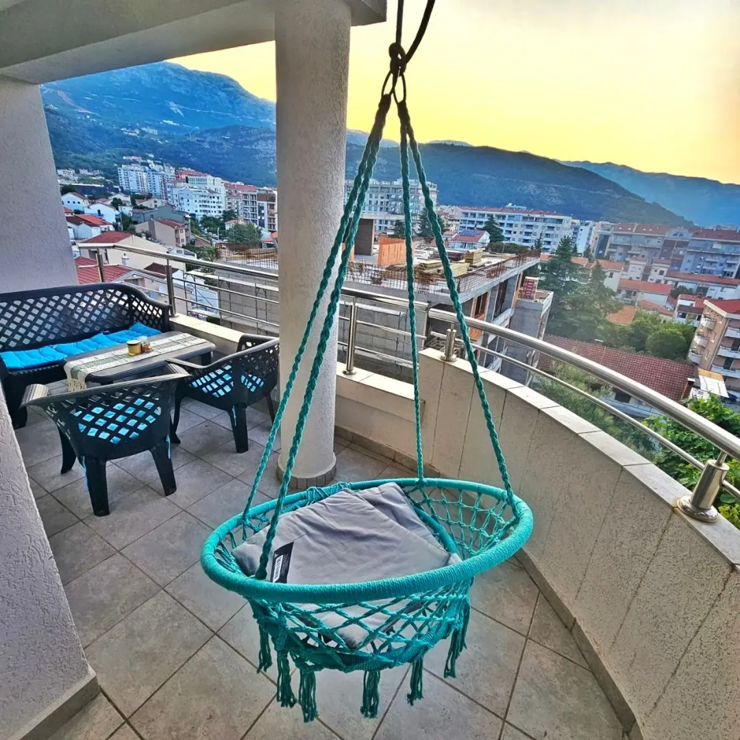 Furnished terrace with a hanging chair and views of the city and mountains.
