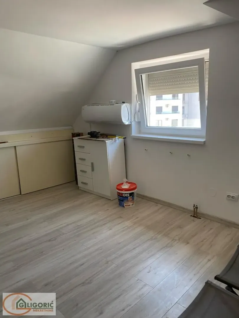 Empty room with sloping ceiling and laminate flooring.
