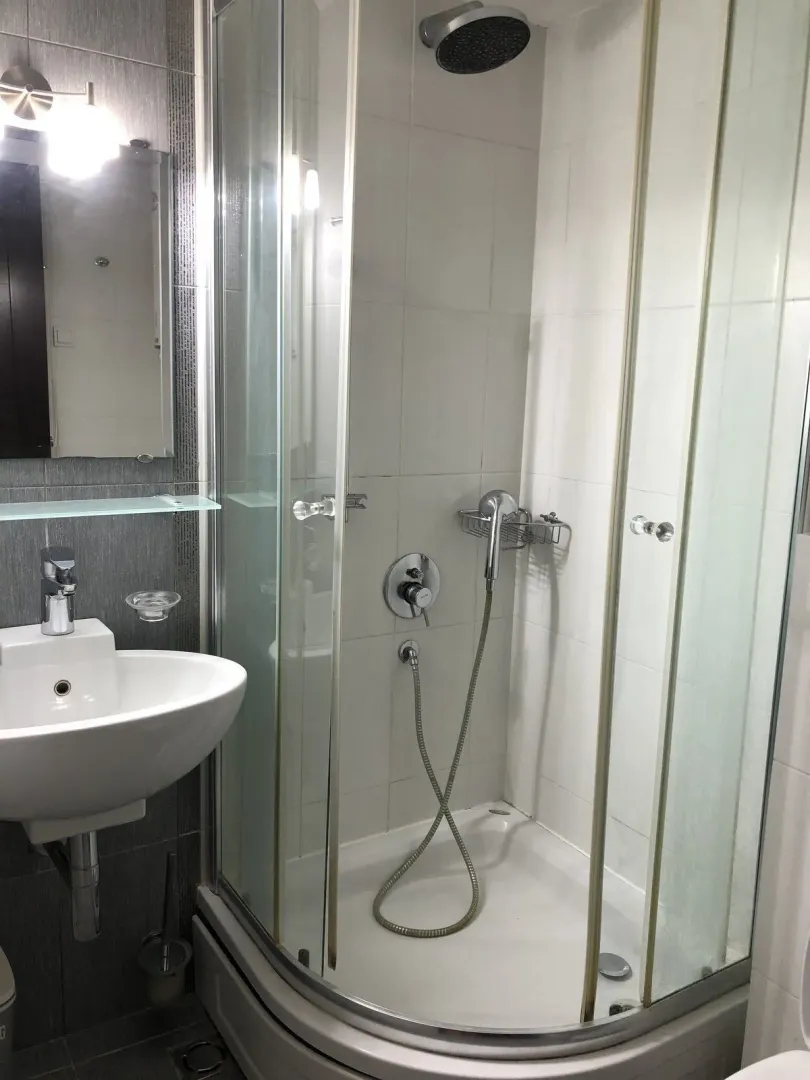 A bathroom with a shower cabin and a white sink.