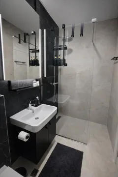 Modern bathroom with a walk-in shower, washbasin, and illuminated mirror. - image 10