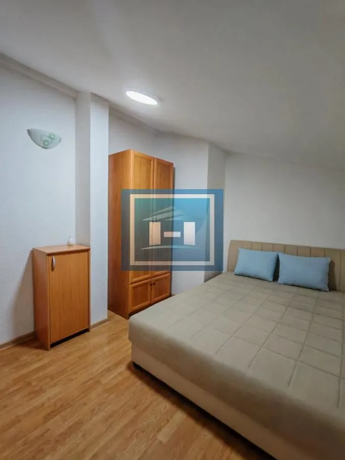 Furnished bedroom with a double bed and a wooden wardrobe.