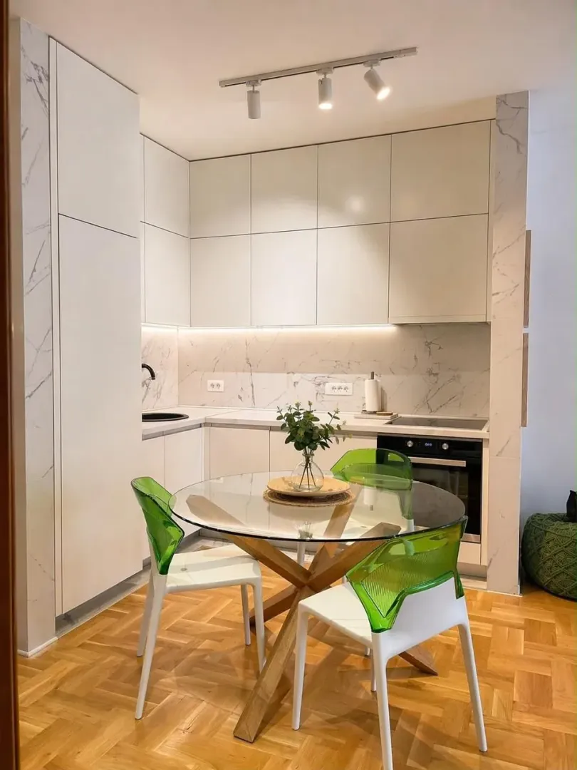 Modern kitchen with a dining table and glass chairs.