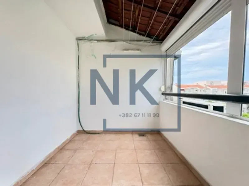 Natkriveni balkon sa popločanim podom i pogledom na okolinu.