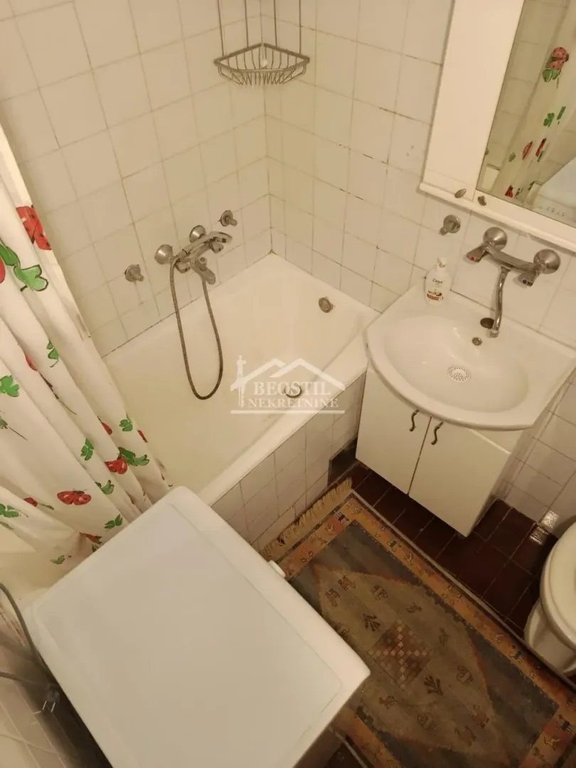 Smaller bathroom with a bathtub, washbasin, and white cabinetry.