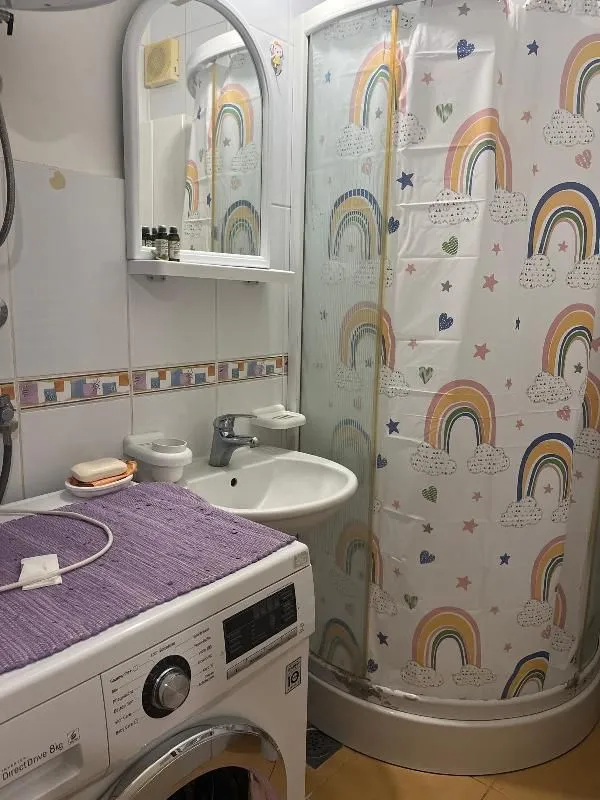 Kupatilo sa umivaonikom, ogledalom, tuš kabinom i veš mašinom.
