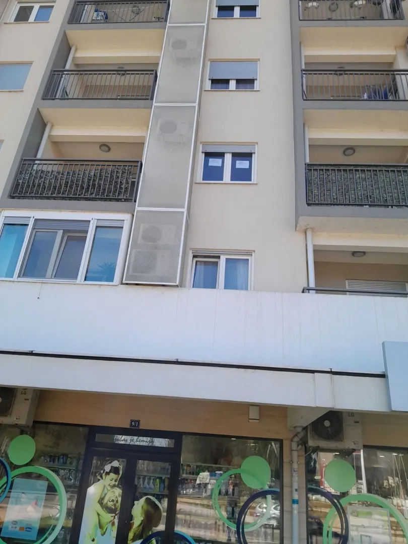 Exterior view of an apartment building with balconies and a ground floor commercial space.