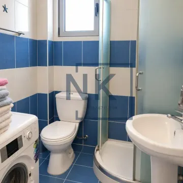 Kupatilo sa plavo-bijelim pločicama, tuš kabinom, umivaonikom, WC šoljom i veš mašinom. - image 2