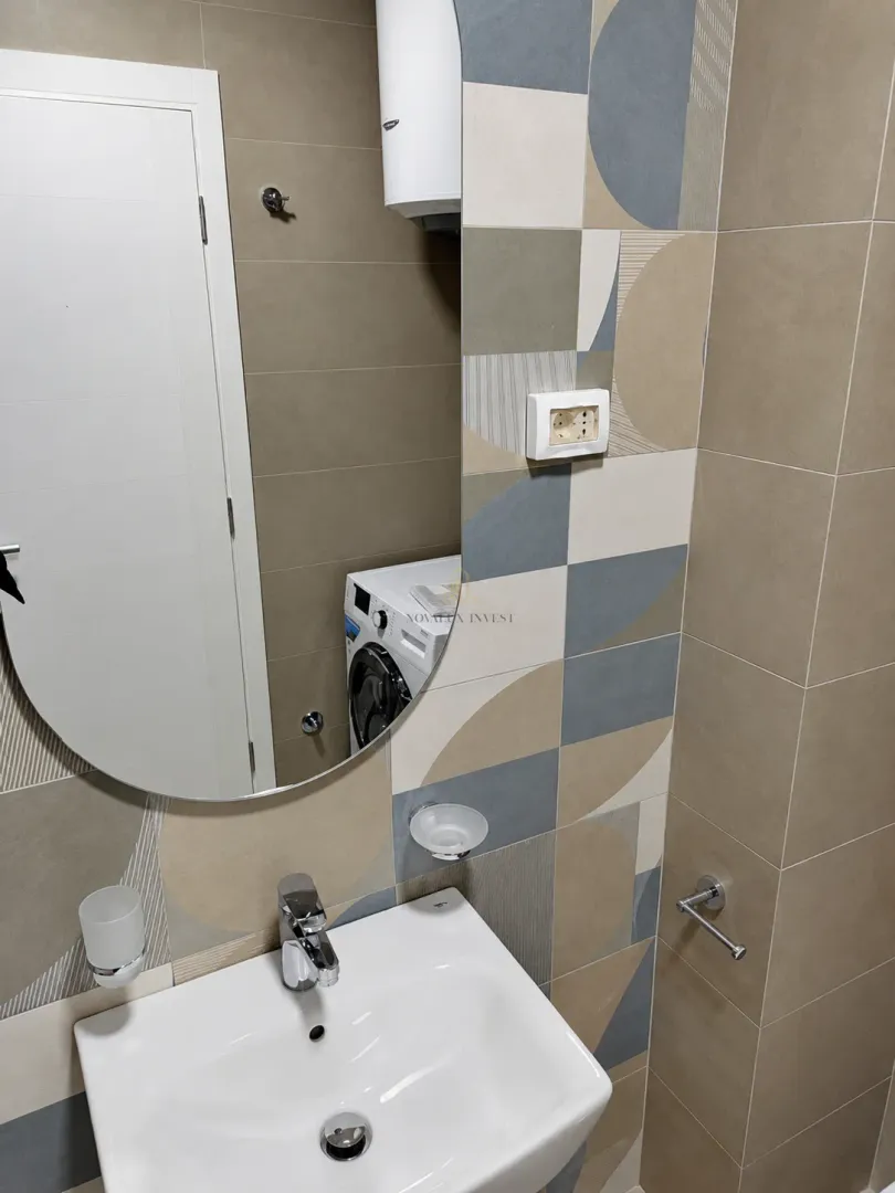 Kupatilo sa umivaonikom, ogledalom i pločicama sa dezenom.