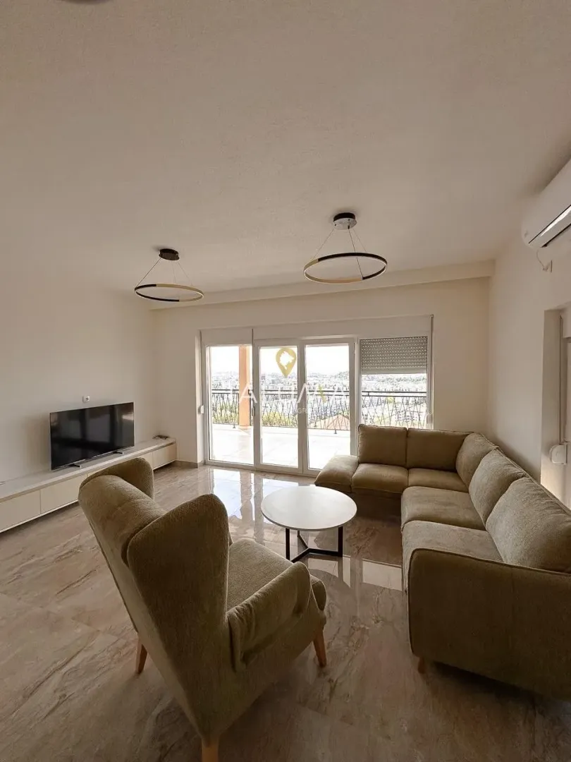 Spacious living room with a sofa set, TV, and access to the terrace.