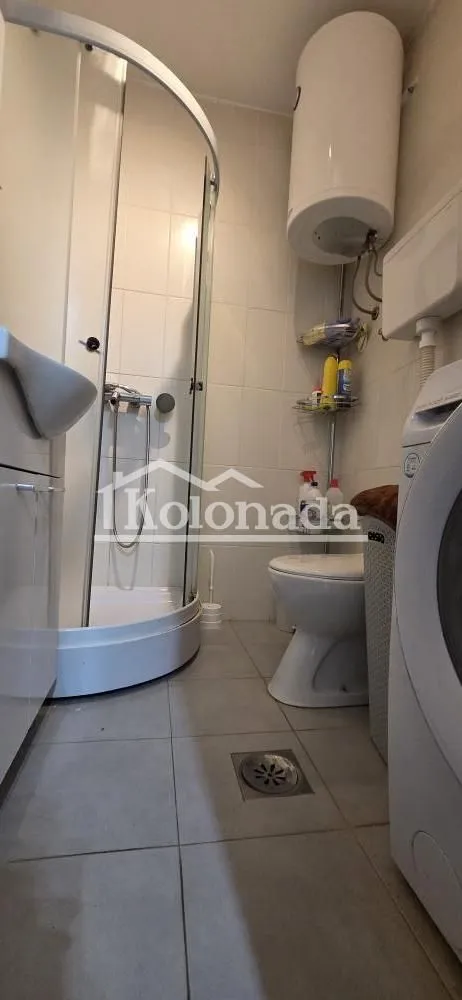 Manje kupatilo sa tuš kabinom, WC šoljom, bojlerom i veš mašinom.