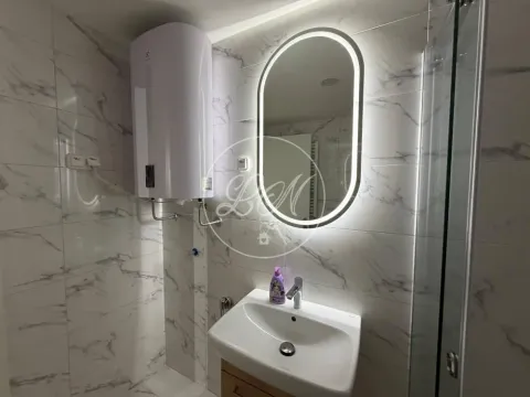 Modern bathroom with a sink, backlit mirror, and water heater. - image 11