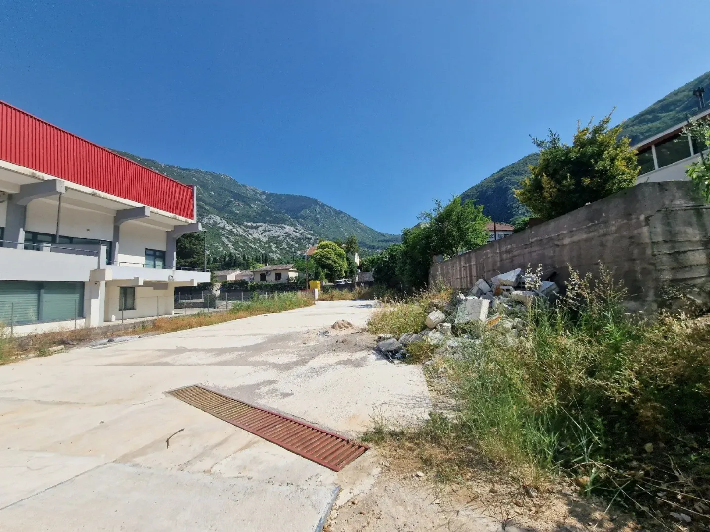 Pogled na spoljašnji prostor sa betonskim platoom i okolnim objektima.