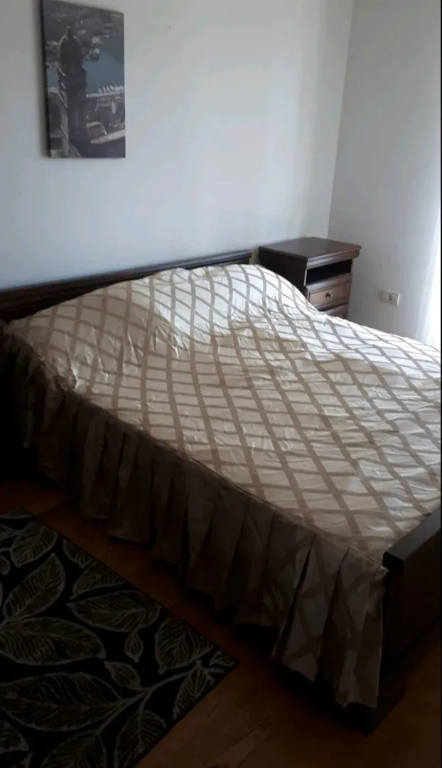 Namještena spavaća soba sa bračnim krevetom i noćnim stočićem.