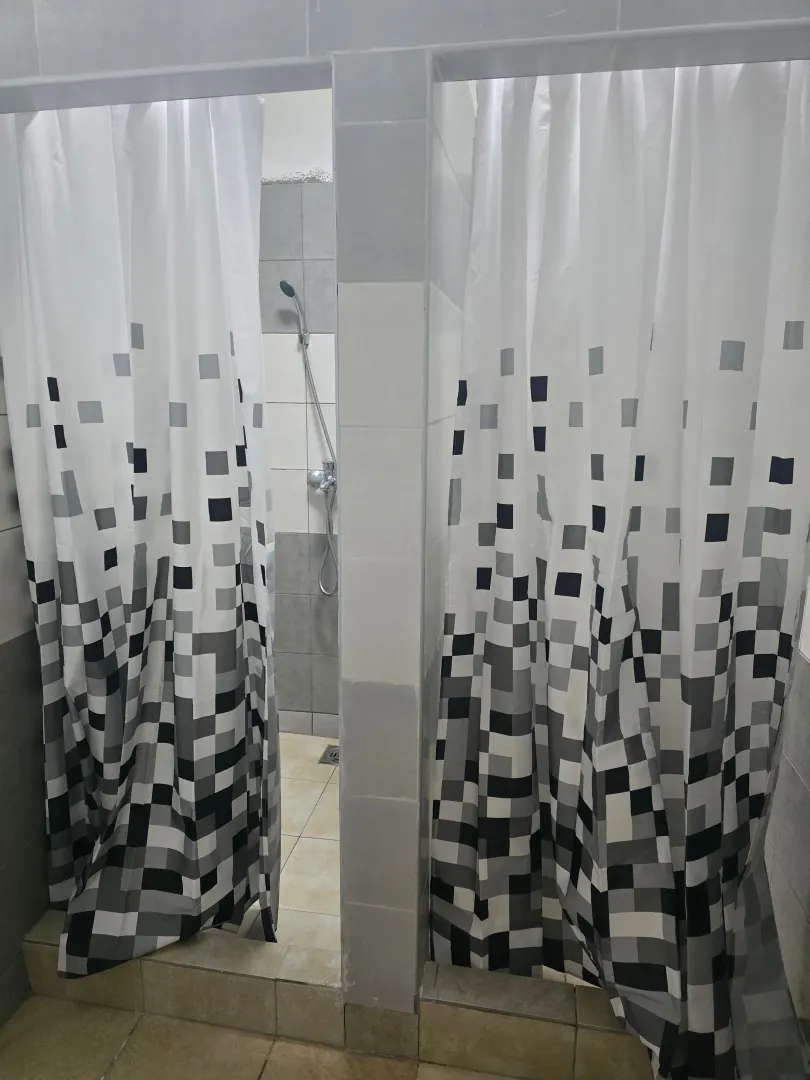 Tuš kabina sa belim zavesama sa šarama u kupatilu.