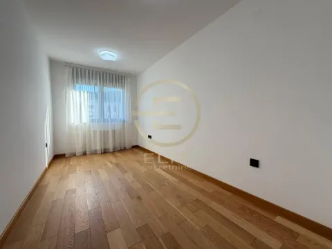 Prazna soba sa belim zidovima, drvenim podom i prozorom sa zavesama. - image 17