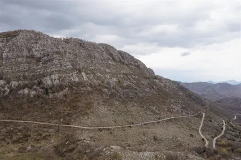 Planinski predio sa krivudavim putem pod oblačnim nebom. - image 12