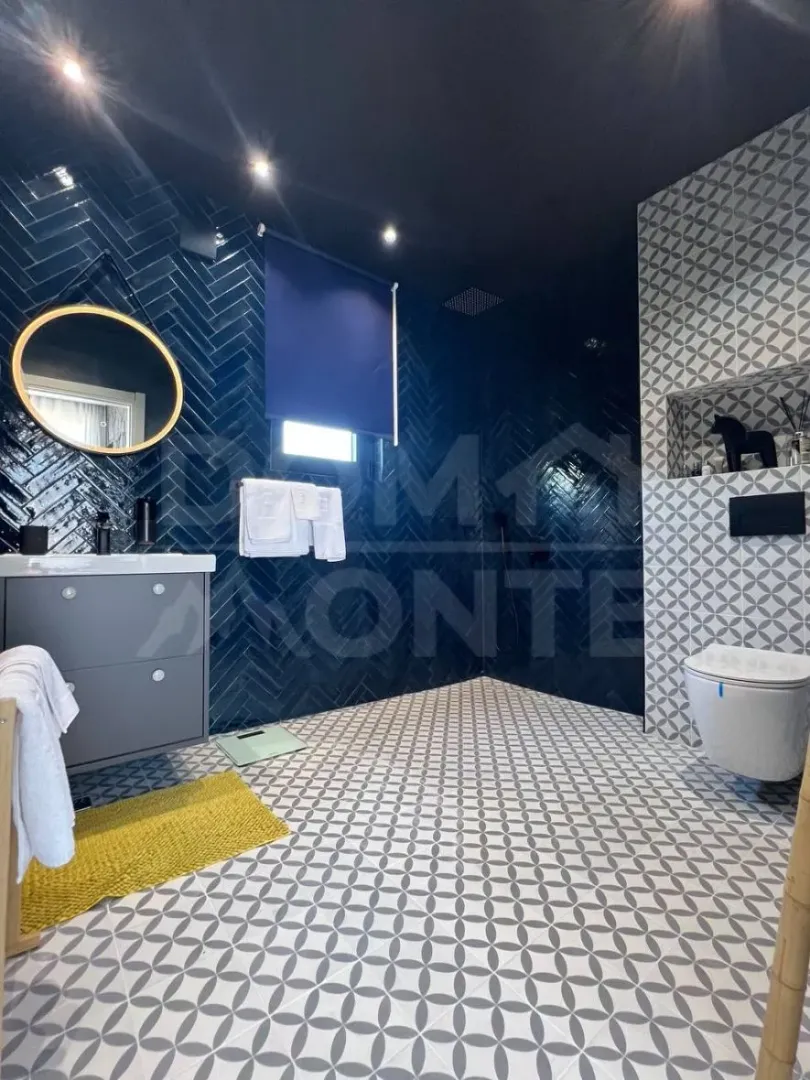 Modernly equipped bathroom with dark blue tiles and sanitary ware.