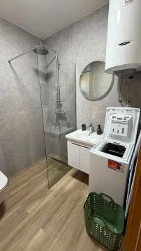 Modern bathroom with a walk-in shower, washbasin, and washing machine. - image 8