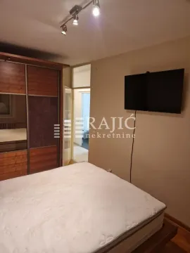 Furnished bedroom with a double bed, wardrobe, and wall-mounted TV. - image 8