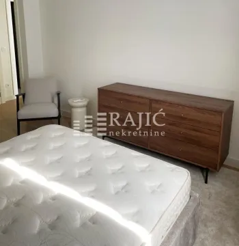 Furnished bedroom with a double bed, armchair, and chest of drawers. - image 7
