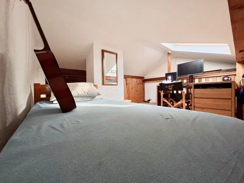 Attic space furnished with a bed and a desk with a computer.