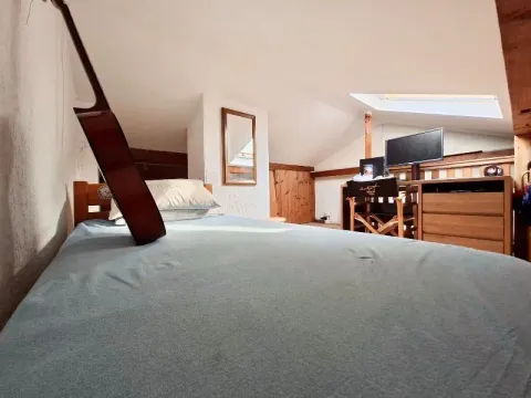 Attic space furnished with a bed and a desk with a computer. - image 10