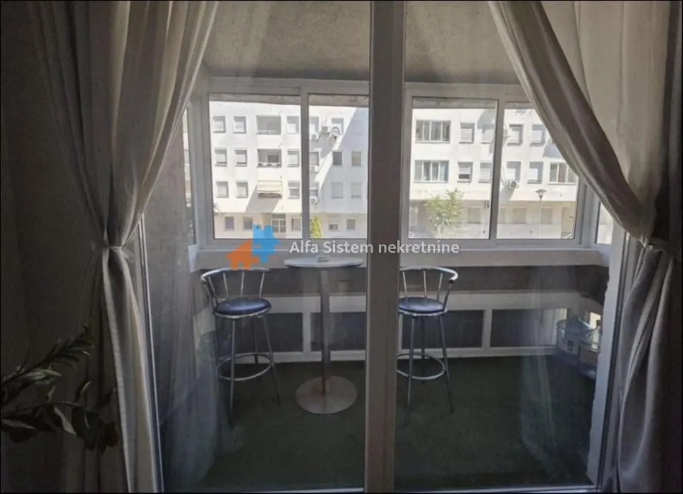 Enclosed balcony with a table and two bar stools.
