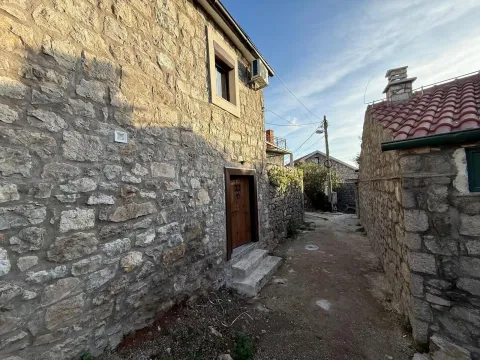 Tradicionalna kamena kuća sa drvenim vratima u uskoj ulici. - image 4
