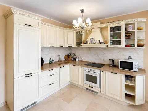 Kitchen equipped with beige cabinets and built-in appliances. - image 4