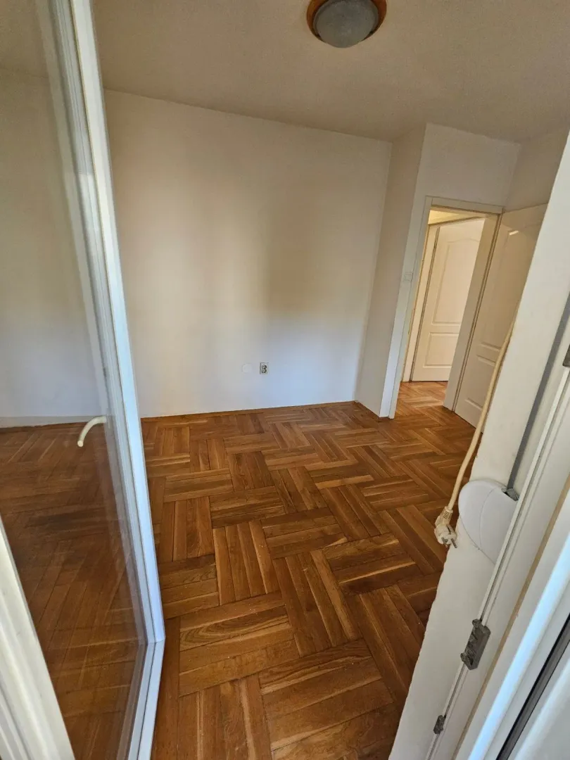 Empty room with parquet flooring and a view of the hallway.