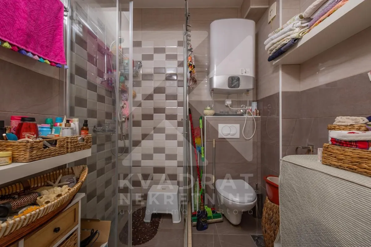 Manje kupatilo sa tuš kabinom, WC šoljom i bojlerom.