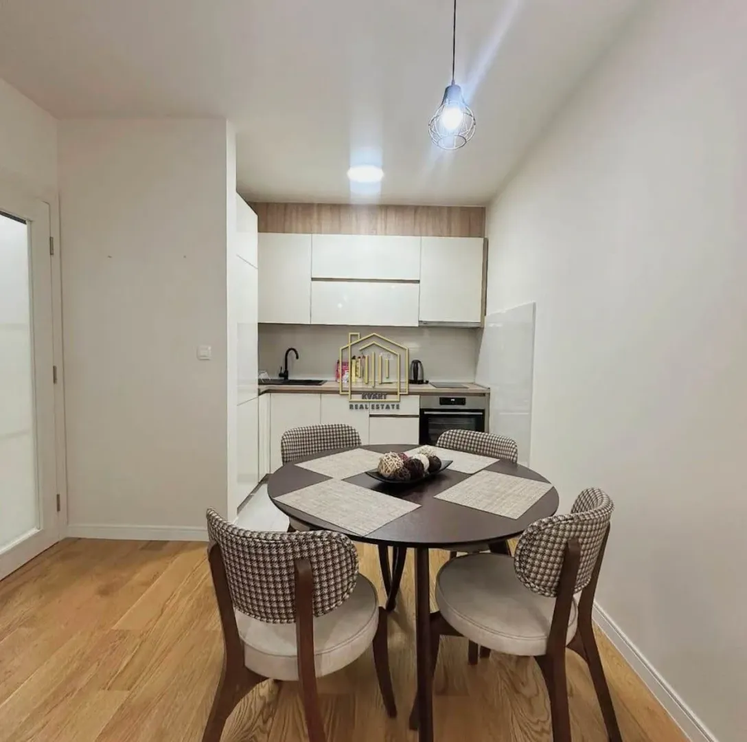 Dining area with a round table and a built-in kitchen in the background.