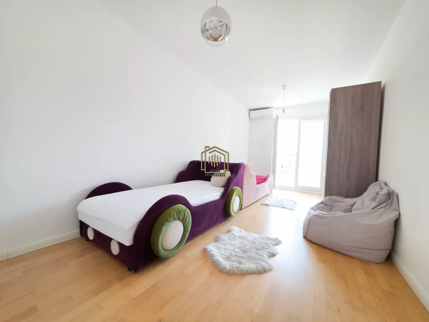 Children's bedroom featuring a car-shaped bed, a wardrobe, and a bean bag chair.