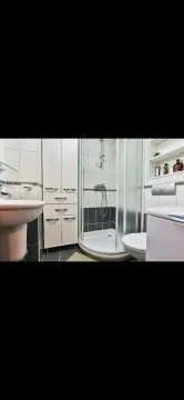 Compactly arranged bathroom with a shower cabin, sink, and white storage units. - image 12