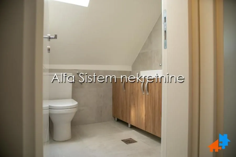 A view of the bathroom with sanitaryware and a wooden cabinet under the slanted ceiling.