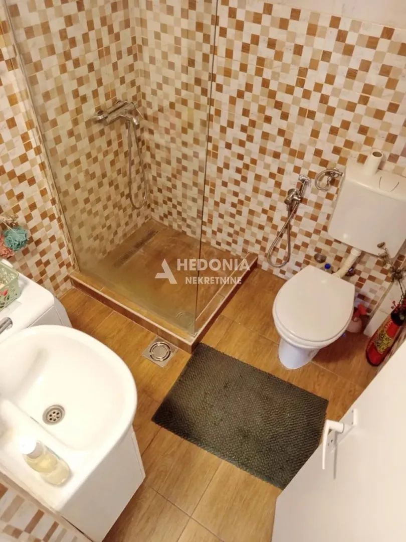 Smaller bathroom with a shower cabin, sink, and toilet.